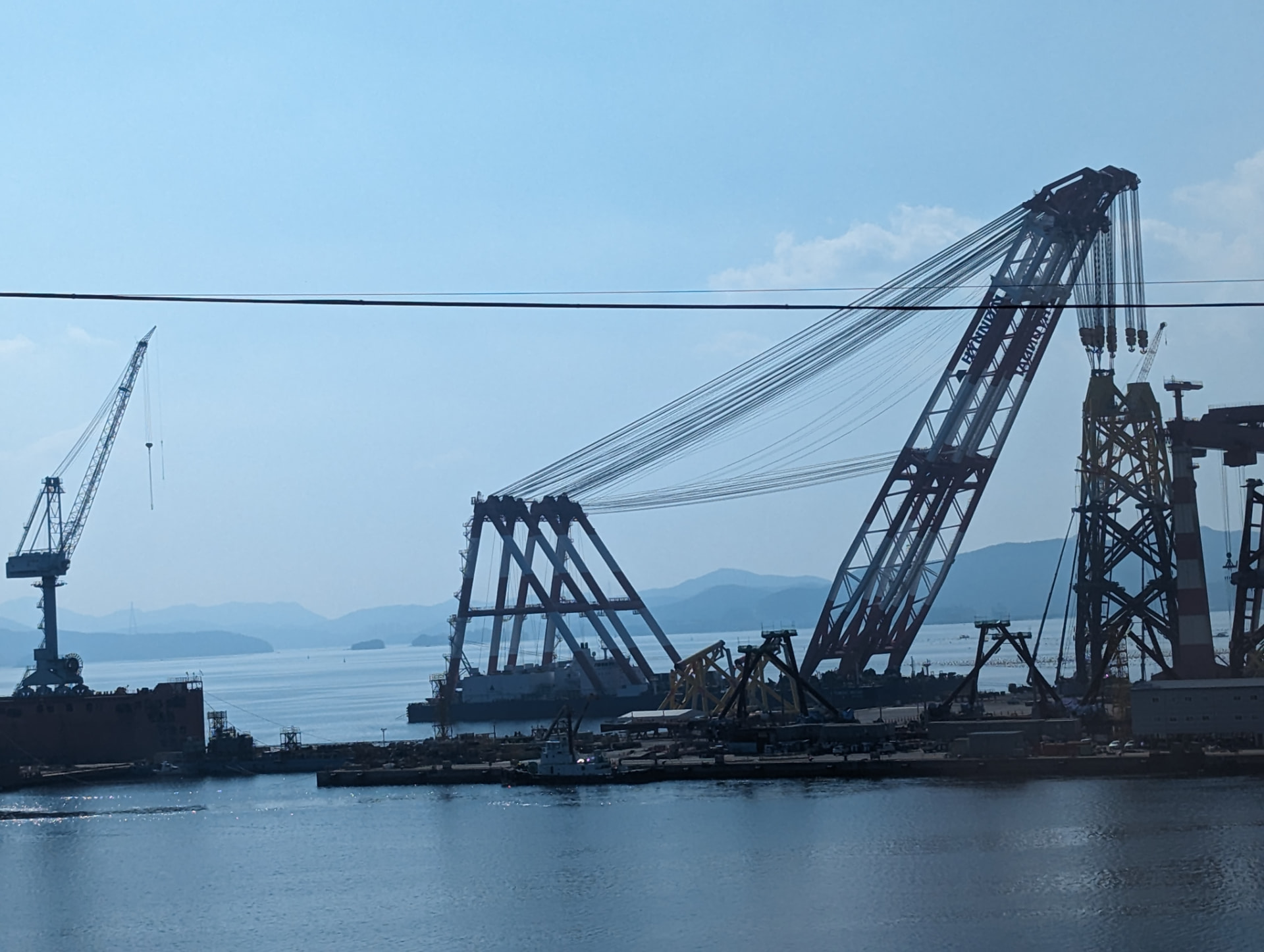 Heavy lift sheerleg crane barge alongside a marine construction yard