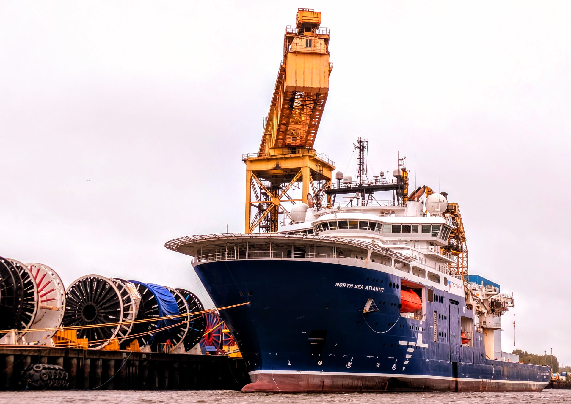 Offshore construction support vessel alongside quay with cable carousels